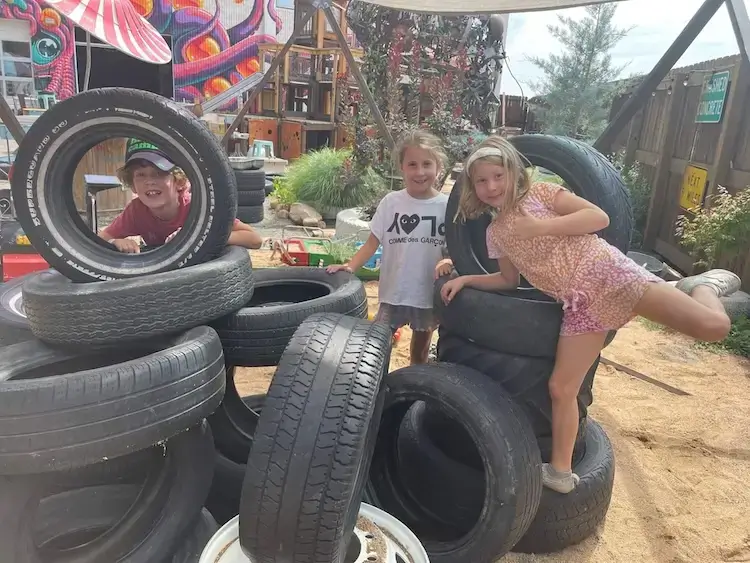 Three kids playing on a pile of old tires