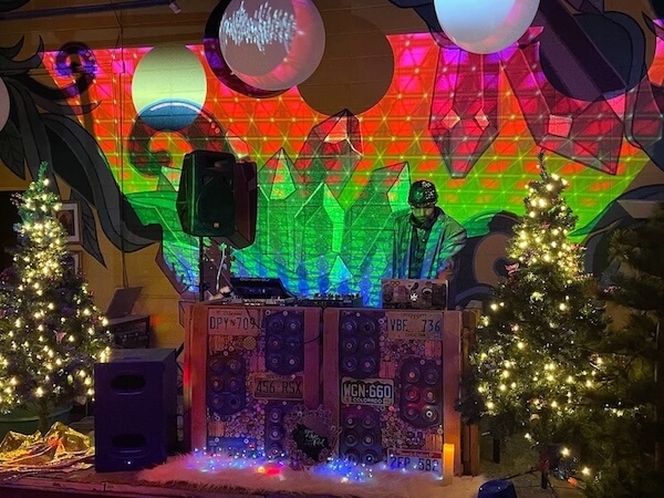 DJ in front of a colorful background inside at the Junkyard